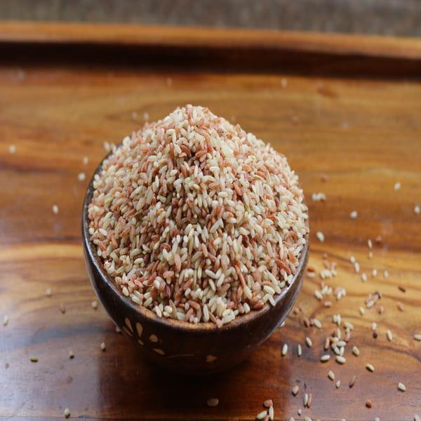 Close-up of Rajamudi red rice in a wooden bowl, showcasing its natural mix of red-brown and off-white grains