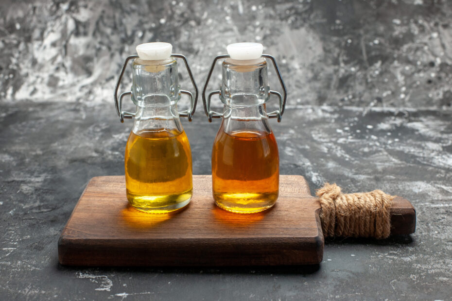wo glass bottles of cold-pressed oil on a wooden board – Aara Living healthy cooking oils blog