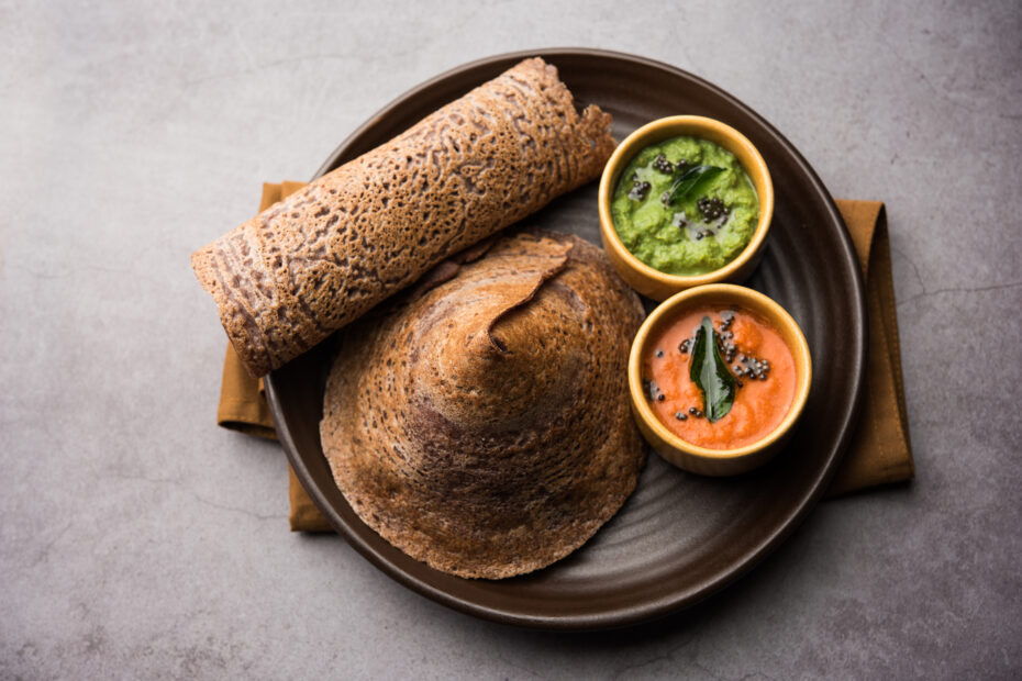 Crispy sprouted ragi (Finger millet) dosa served with green coconut chutney and red chutney on a rustic plate Aara Living