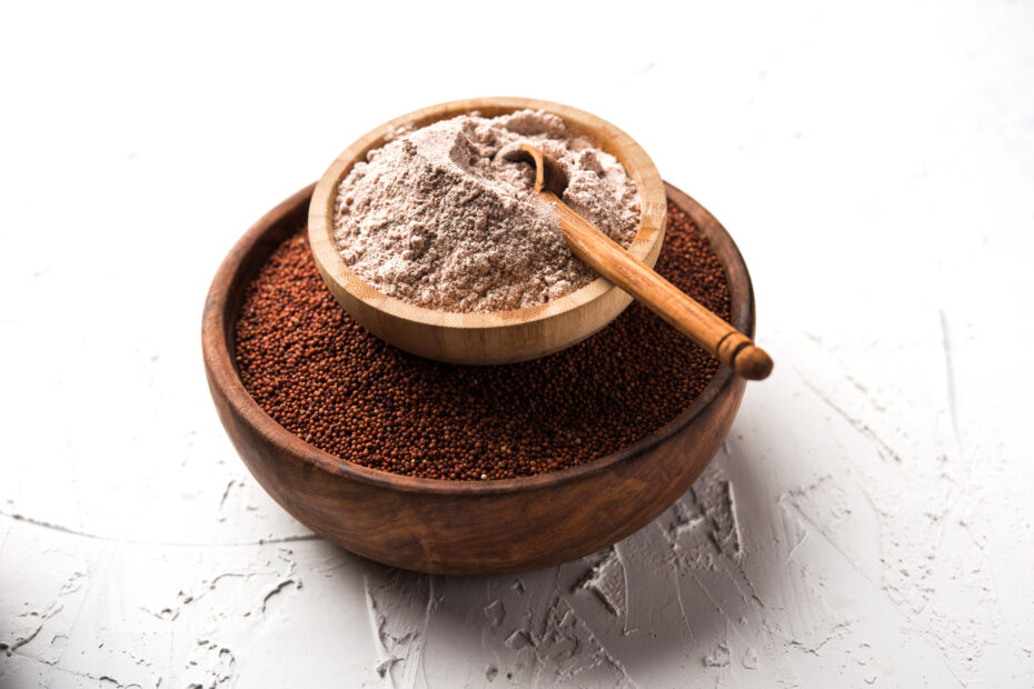 Sprouted ragi flour in wooden bowl with whole ragi millet