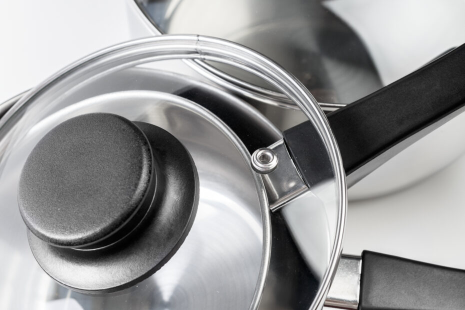 Triply stainless steel pots and pans set with glass lids on a white background