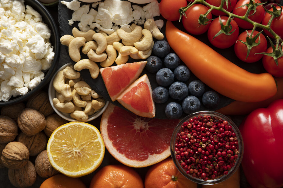 Colorful assortment of plant-based iron sources like cashews, walnuts, tomatoes, peppers, and berries alongside vitamin C-rich citrus fruits to highlight better iron absorption.