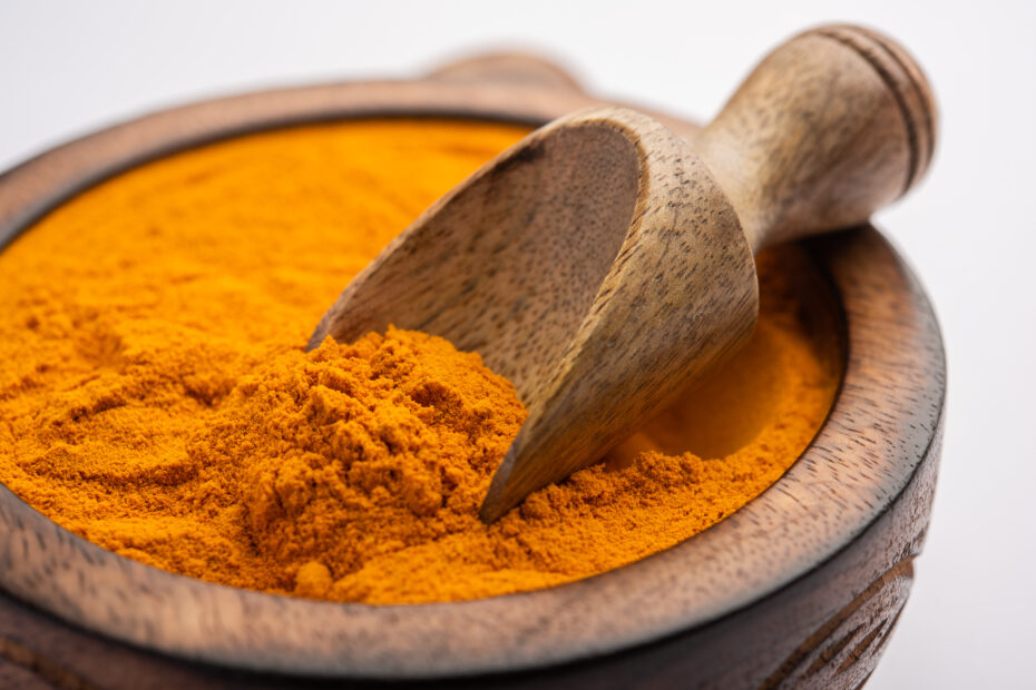 Lakadong turmeric powder in a wooden bowl with scoop, known for its rich curcumin content that boosts immunity and reduces inflammation.