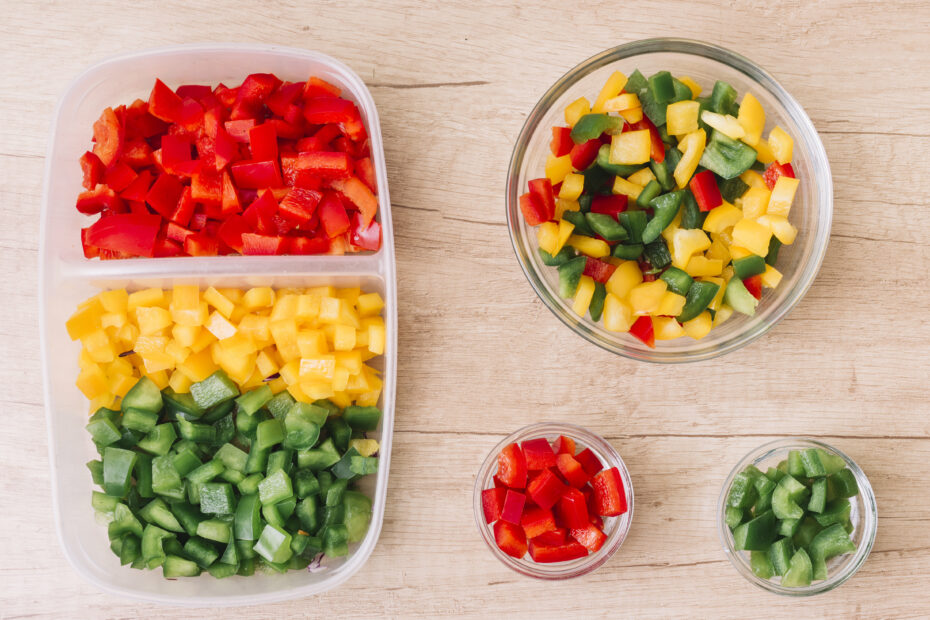 Top view of chopped red, yellow, and green bell peppers neatly arranged in a tray and bowls – perfect for weekly Indian kitchen meal prep. Aara Living